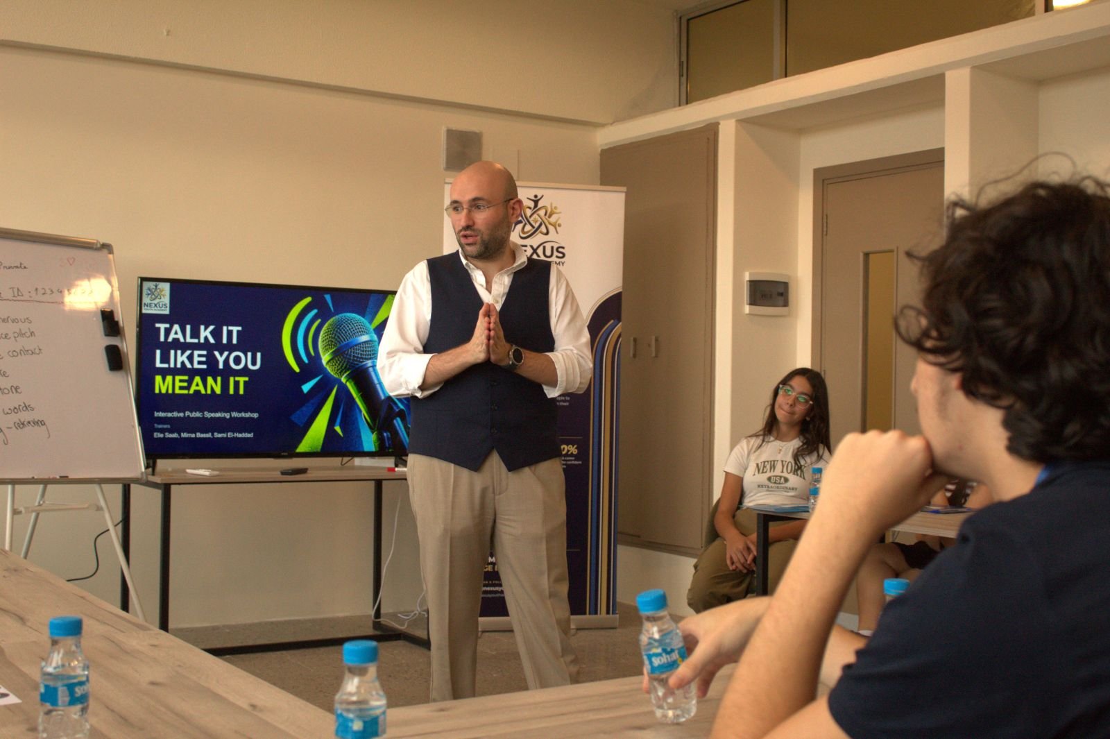 A trainer speaking to students in front of the Talk It Like You Mean It slide