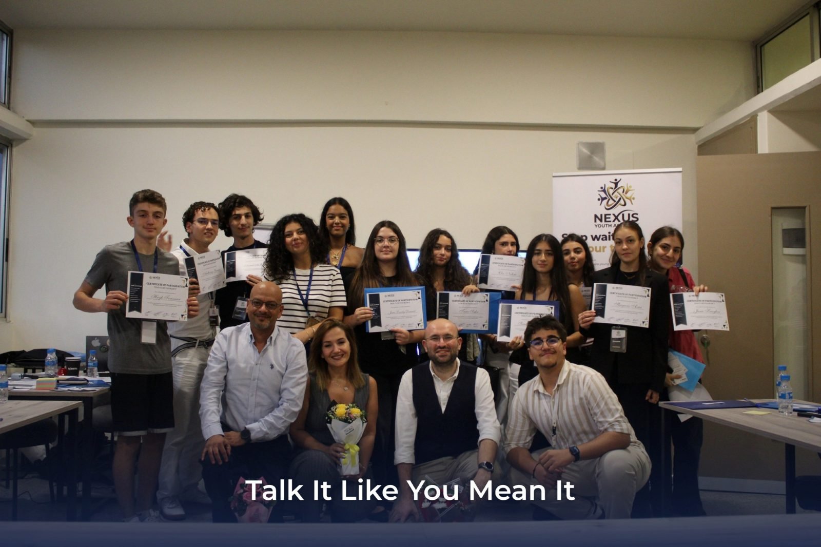 Students and trainers holding their certificates at the end of the Talk It Like You Mean It workshop
